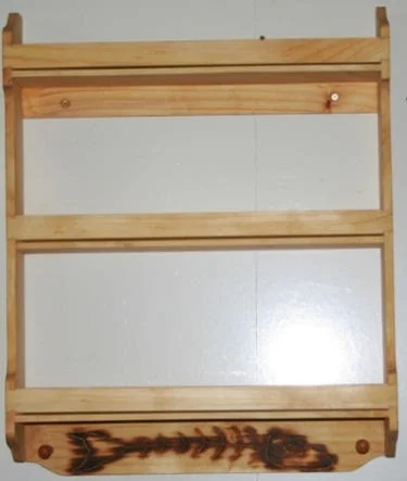 Pine spice rack on sale. 3 tier Pine wood spice rack dimensions. 17" tall, 14" wide, 3" deep. Top and bottom shelf on wooden wall hung spice rack in classical design will hold all your spice bottles up to 2 1/2" diameter. Up to 6" tall. Top and bottom shelves are 3" deep. Middle shelf on Dave's wall hung 14" Pine wood spice rack plan will hold all your spice bottles up to 2" diameter. Up to 6" tall. Middle shelf is 2 1/2" deep. 14" Pine kitchen rack comes with 3 shelves and 2 key pegs for hanging your keys or pot pads.